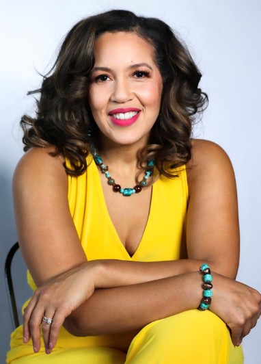 Dr. Alicia Watkins in a vibrant yellow outfit, smiling warmly